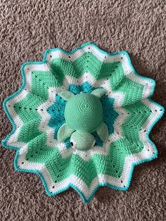 a crocheted green and white flower on the floor