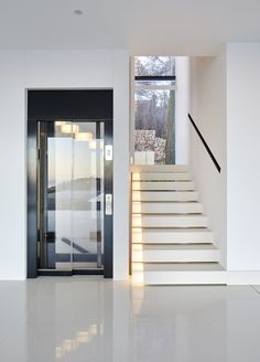 an open door leading up to a white staircase with glass doors and railings on both sides