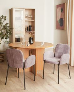 two chairs sitting at a round table in front of a cabinet with wine glasses on it