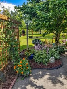 a garden with lots of plants and flowers in it's center area next to a wooden trellis