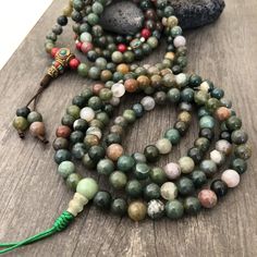 Beautiful Mix Jade Japa Mala from Nepal. You can choose between the mala that has unique mix metal beads and a main Nepali metal bead at the bottom of the mala necklace. Or the mix Jade mala that is all stone beads with no metal beads. A unique praying mala that can be used as a necklace or as an ornament. The mala has no clasp, you wear it over the head. The Mala with the metal beads and the red beads has a total length of 49cm- 19.25 inch long The mala that is all stone beads is 43cm- 17 inch Holistic Beaded Bracelets With Round Beads For Meditation, Multicolor Polished Beads Bracelet For Meditation, Handmade Jade Beaded Necklaces, Multicolor Polished Beaded Bracelets For Meditation, Green Mala With 8mm Beads For Healing, Green Spiritual Beads, 108 Count, Bohemian Beaded Round Mala, Adjustable Jade Beaded Necklace With 8mm Beads, Multicolor Jade Beaded Bracelets With 8mm Beads