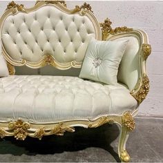 a white and gold couch with pillows on it