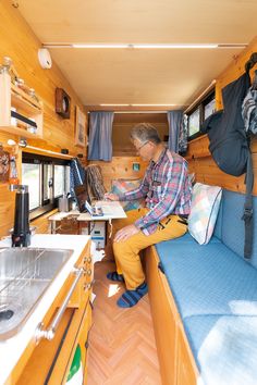 a man sitting on a couch inside of a small room next to a stove top oven