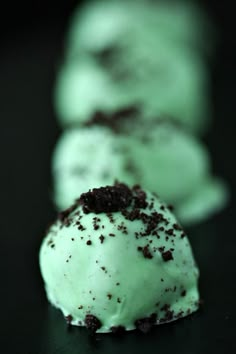 three desserts with green frosting and chocolate sprinkles on black surface