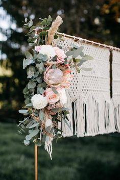 a wedding arch with flowers and greenery hanging from it's sides in the grass