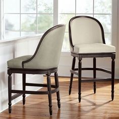 two chairs sitting next to each other on a wooden floor in front of a window