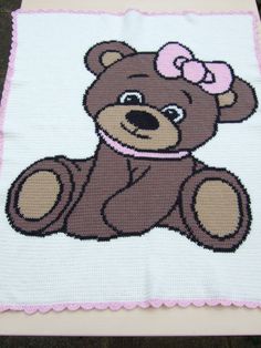 a brown teddy bear with a pink bow on it's head sitting on a white cloth