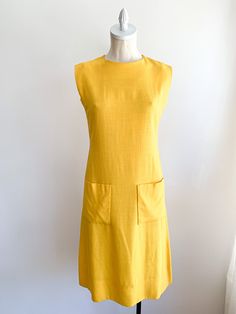 Happy yellow structured dress with subtle luxury detailing. Missing original belt. We suggest adding a rope or skinny belt for a modern update to complete this classic look. Front pockets and hidden back zip. Fabric: Linen blendLabel: Pauline TrigèreFit: SEra: 1960/70’s Measurements: Bust 34" Shoulder 16" Length 41" Waist 30" Hips 38" Condition: Very good. Very slight pulling at left arm seam (see photo). Yellow Sheath Midi Dress For Work, Yellow Midi Dress With Pockets, Yellow Knee-length Dresses With Pockets, Chic Mustard Workwear Dress, Mustard Chic Dress For Work, Chic Mustard Dress For Work, Yellow A-line Midi Dress For Work, Happy Yellow, Structured Dress