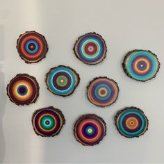 several pieces of wood that have been painted with multicolored circles on them, sitting on a white surface