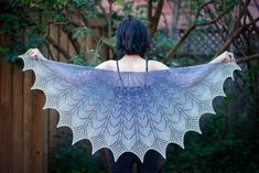 a woman is holding up a shawl in her hands