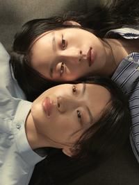 two young people laying on the floor with their heads resting on each other's shoulders