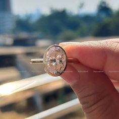 a person holding a ring with a diamond in it's middle and the other hand