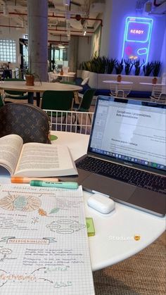 an open laptop computer sitting on top of a table next to a notebook and pen