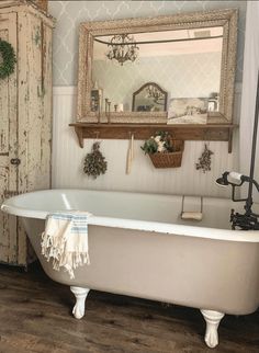 an old fashioned bathtub in a bathroom with wood flooring and white paint on the walls