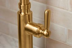 a gold faucet mounted to the side of a white brick wall