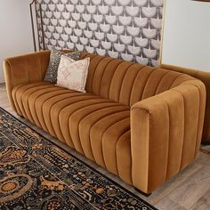 a brown couch sitting on top of a wooden floor next to a rug and lamp