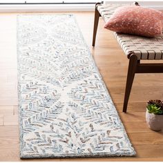 a white rug on the floor in front of a chair and window with a plant