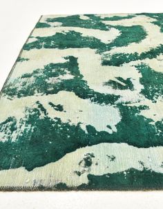 a green and white area rug with an abstract design on the bottom, in front of a white background