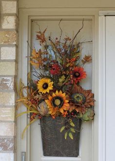 a basket filled with sunflowers and other flowers on the front door sill