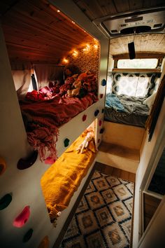 the interior of a small camper with bunk beds and lights in the window area