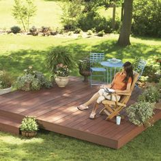 a woman sitting in a chair on top of a wooden deck