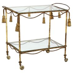 a brass and glass bar cart with bells on wheels