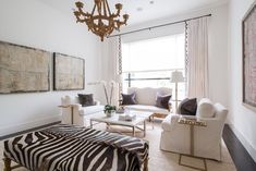 a living room filled with white furniture and a chandelier hanging from the ceiling