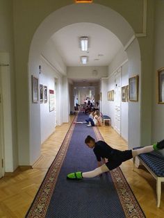 a young boy laying on the floor in an empty hallway with his legs stretched out