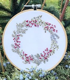 a white embroidery hoop with red berries and green leaves