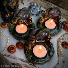 candles are lit in the middle of a table with pumpkins and other decorations on it