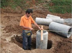 a man in an orange shirt is working on pipe laying around the hole with a rope