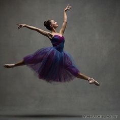 a ballerina in purple and blue is doing a trick