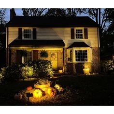 a house lit up at night with pumpkins in the front yard