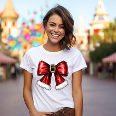 Get ready to spread festive cheer with our Christmas Santa Bow Shirt! This adorable shirt combines the charm of a Christmas coquette style with a delightful retro Christmas tee design, making it the perfect addition to your holiday wardrobe. Featuring a cute pink bow and a cheerful Santa Claus, this Christmas bow shirt is not only stylish but also cozy, resembling a vintage Christmas sweatshirt. Whether you're shopping for yourself or looking for Christmas gifts for loved ones, this girlie Chris Festive Christmas Top, Red Holiday Shirt For Gift, Holiday Red Shirt As Gift, Red Holiday Shirt Gift, Red Christmas Top For Gift, Red Christmas Tops As Gift, Red Christmas Top As Gift, White Festive Christmas Shirt, White Festive Shirt For Christmas