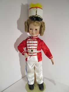 a doll is dressed in a red and white uniform with a hat on it's head