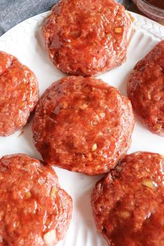 several hamburger patties on a white plate with ketchup