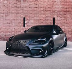 a black car parked in front of a brick wall