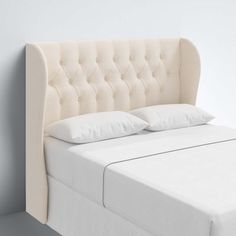 a bed with white sheets and pillows on top of it in a room next to a wall