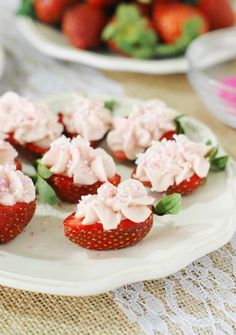 strawberry cupcakes with white frosting and green leaves on a plate, ready to be eaten