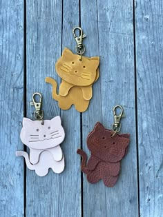 three leather key chains with cats on them