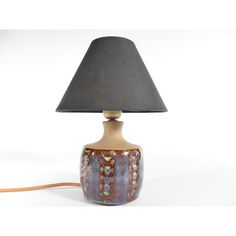 a table lamp with a black shade on it and a cord plugged into the base