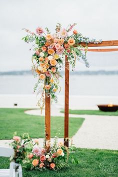 an outdoor ceremony setup with flowers and greenery on the grass by the water in the background