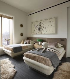 two beds in a room with large windows and rugs on the floor next to them