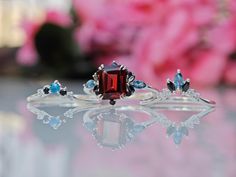 two rings with different colored stones on top of each other and flowers in the background