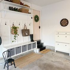 a living room with white walls and lots of storage space on the wall next to a black chair