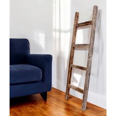 an old wooden ladder leaning against the wall next to a blue chair in a white room