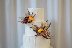 a three tiered white cake with yellow flowers on top