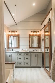 a large bathroom with two sinks, mirrors and lights on the ceiling is shown in this image