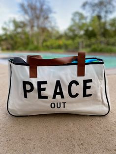 Tote around your daily essentials in this super chic PEACE OUT large canvas tote bag! Sling this bad boy over your shoulder as you go about your day, stylishly proclaiming your inner chill and total mindfulness. With its large size, you can fit everyone's needs in one bag (talk about making peace)! Perfect for weekend getaways, lake days, beach days and more! Made of canvas and brown vegan leather 20" wide 11" tall 5" deep Casual Canvas Beach Bag For Weekend, Casual Canvas-lined Shoulder Bag For Weekend, Casual Shoulder Bag With Canvas Lining For Weekend, Casual White Beach Bag With Canvas Lining, White Canvas Bag For The Weekend, Casual Weekend Canvas Tote Bag, Casual White Canvas Bag For Weekend, Casual Canvas Bags For Weekend, White Casual Canvas Bag For Weekend