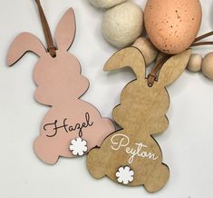 two wooden tags with the words happy easter written on them next to eggs and flowers